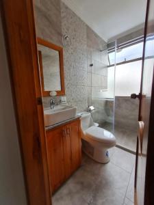 y baño con aseo, lavabo y espejo. en Hostal Morlaquita en Cuenca