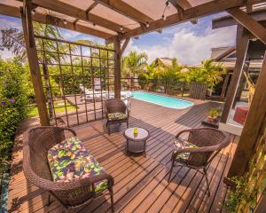 una terrazza in legno con sedie e una piscina di Villa Suhr Cabanas a Praia do Rosa