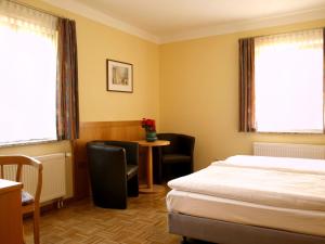 a hotel room with a bed and a table and chairs at Hotel Dom-Eck in Bautzen