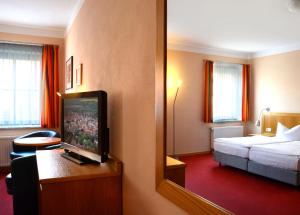 a hotel room with a bedroom with a bed and a mirror at Hotel Dom-Eck in Bautzen