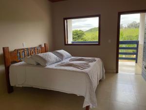a bedroom with a bed and a window with a view at Tijota Hotel Fazenda in Ipatinga