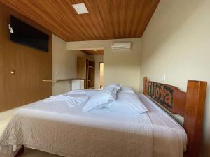 a bedroom with a large bed with white pillows at Tijota Hotel Fazenda in Ipatinga