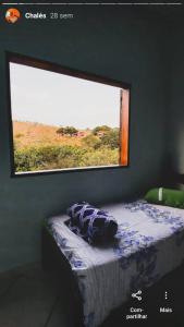 a bedroom with a window and a bed with a comforter at Pousada e Restaurante Boia Cross in Vargem Bonita