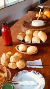 a table with plates of buns and plates of food at Pousada e Restaurante Boia Cross in Vargem Bonita
