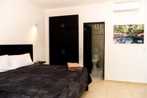 a bedroom with a bed and a bathroom with a toilet at Cenotes Casa Tortuga Tulum in Tulum