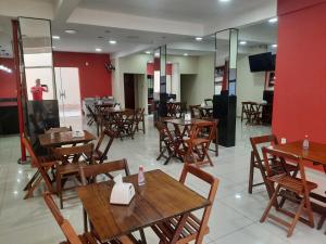 a restaurant with wooden tables and chairs and a red wall at Pousada Mãe Ternura Palace in Aparecida