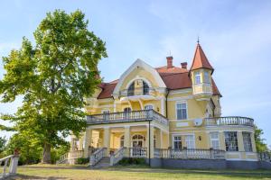 une grande maison jaune avec un arbre en face dans l'établissement Boros Kastély Vendégház, à Fonyód