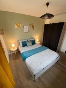 a bedroom with a bed with blue pillows at appartement au coeur de Loupiac in Loupiac-de-Cadillac +8 photos