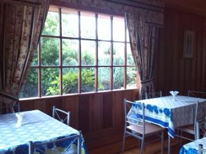 a room with two tables and a large window at Hostal Kutralwe in Pucón