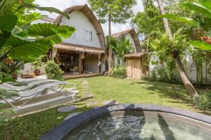 een achtertuin met een zwembad en een huis bij Eco Bamboo Bungalow 3 in Canggu