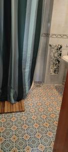 baño con cortina de ducha y suelo de baldosa. en Cosy Studio +netflix+24h entry+silent air conditionning, en Málaga