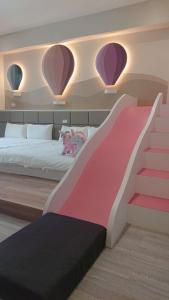 a bedroom with a pink and white bed and a staircase at 胖蝸牛親子民宿 in Anping