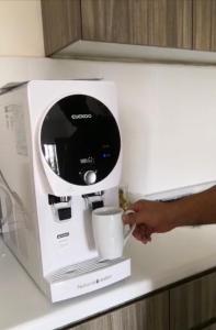 a person holding a cup in front of a coffee machine at Awin swiss garden residence in Kuantan