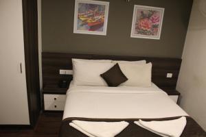 a bedroom with a bed with white sheets and pillows at Hotel Royal Inn - Electronic City in Bangalore