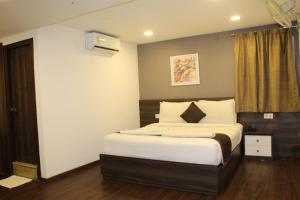 a bedroom with a bed with white sheets and pillows at Hotel Royal Inn - Electronic City in Bangalore