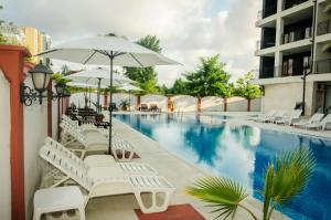 a swimming pool with white lounge chairs and an umbrella at Cantilena Complex in Sunny Beach