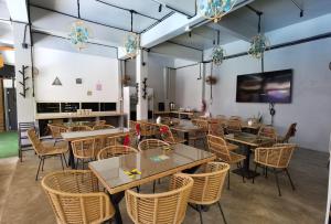 a restaurant with tables and chairs and a flat screen tv at A Coral Reefs Resort Langkawi in Kuah