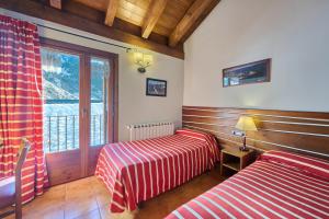 a bedroom with two beds and a window with a view at Aparthotel Areu in Areu