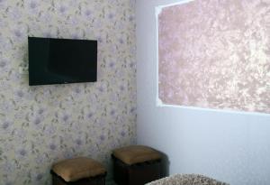 a room with a tv on a wall with two stools at Hotel Kambuz in Sevan