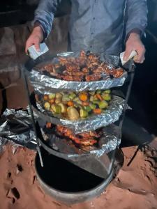 a man is cooking food on a barbecue grill at Rum Panoramic Camp & Tour in Wadi Rum