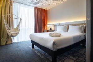 une chambre d'hôtel avec un lit et un hamac suspendu dans l'établissement ibis Almaty Jetisu, à Almaty