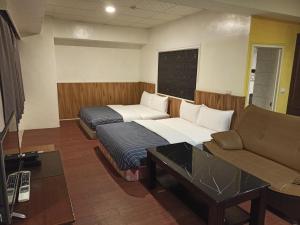 a hotel room with two beds and a couch at 九族飯店 臺東縣旅館004號 in Wenquan