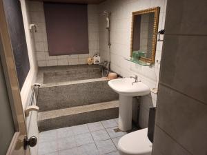 La salle de bains est pourvue d'un lavabo, d'une baignoire et de toilettes. dans l'établissement 九族飯店 臺東縣旅館004號, à Wenquan