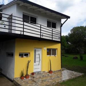 a yellow and white house with potted plants in front of it at Cabaña Los Pinos in Villa Icho Cruz