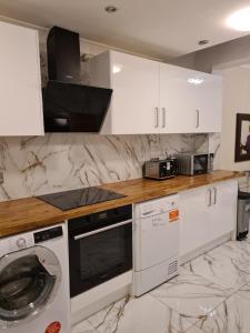 a kitchen with white cabinets and a washer and dryer at Umbrella Properties London Excel in London