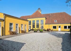 a large yellow building with tables and chairs in the courtyard at Børglum Mejeri Hotel in Børglum