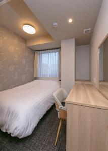 a bedroom with a bed and a desk and a chair at Remington Hotel in Akashi