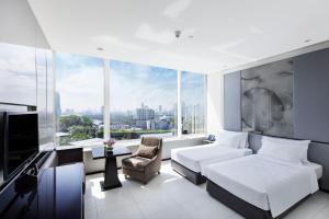 a bedroom with a bed and a couch and a tv at Grande Centre Point Hotel Terminal21 in Bangkok