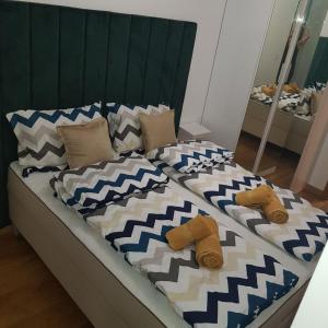 a bed with blue and white blankets and pillows at SNP city center lux in Novi Sad