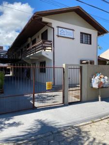 una casa blanca con una valla delante en Pousada Villa Garcia - Residencial, en Florianópolis