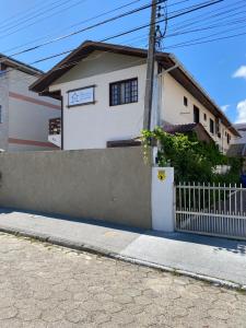 una casa blanca con una valla delante en Pousada Villa Garcia - Residencial, en Florianópolis