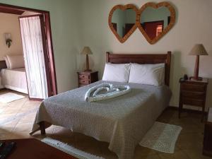 Pousada Mar a Mar في بوزيوس: غرفة نوم مع سرير ومرآة قلب على الحائط