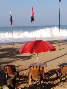 zwei Stühle und ein roter Sonnenschirm am Strand in der Unterkunft Villa seaside in Bentota