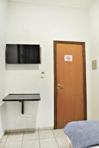 a room with a door and a flat screen tv at Ribeirão Plaza Hotel in Ribeirão Preto