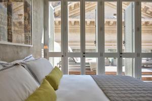 a bedroom with a white bed with a large window at Casa Ellul - Small Luxury Hotels of the World in Valletta