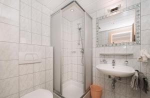 baño blanco con ducha y lavamanos en Berghotel Bodenalpe, en Ischgl