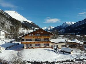 a hotel in the snow with mountains in the background at Hotel Panorama in Elbigenalp