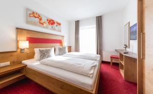 a bedroom with a large bed and a desk at Landhaus Rosengartl in Schladming