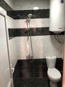 ein schwarz-weißes Bad mit einem WC und einer Dusche in der Unterkunft River side SVANETI in Mestia