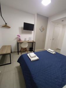a room with a blue bed with a table and a desk at GiglioApartment Etna Mare in Aci Castello +14 photos