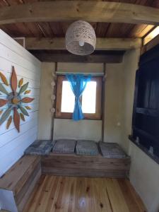 Habitación con ventana y almohadas azules. en Flor de Vida Geocabañas - Tiny, en La Esmeralda