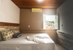 a bedroom with a bed with a window at Roncador Suítes in Lençóis