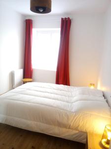 1 dormitorio con cama blanca y cortinas rojas en Champeix, maison confort 6 personnes en Champeix