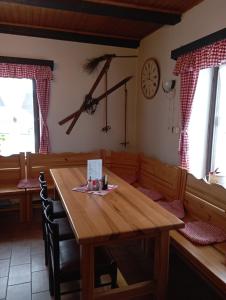 uma sala de jantar com uma mesa de madeira e um relógio na parede em Penzion Hraničář em Loucná pod Klínovcem