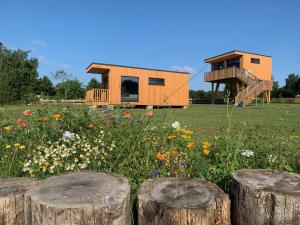 a tiny house in a field with flowers and logs at Kanal 33 in Schafstedt