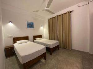 1 Schlafzimmer mit 2 Betten und einem Vorhang in der Unterkunft Kalan Mirissa in Mirissa